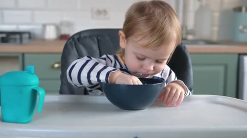 Little Child Eating Food in Kitchen