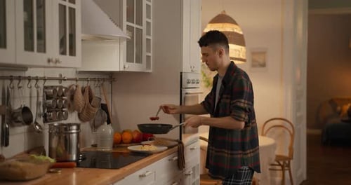 Young Man Cooking Pasta in Bright Home Kitchen