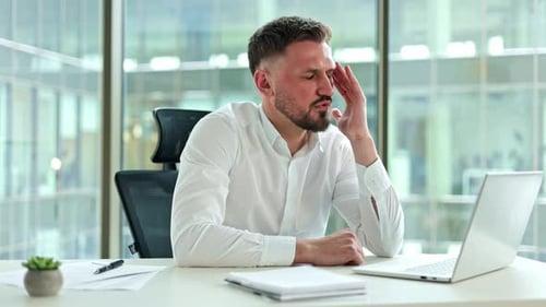 Businessman Suffering From Headache While Working on Laptop in Office
