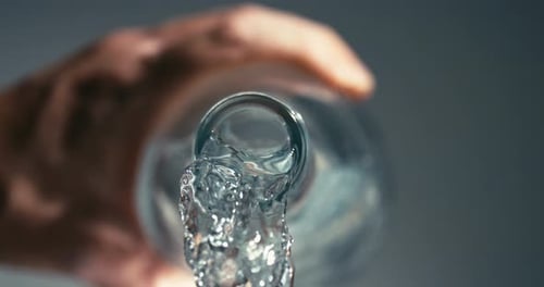 Clear Water Flowing from Glass Bottle in Close Up