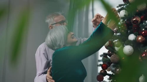 Senior Couple Decorating Christmas Tree Together at Home