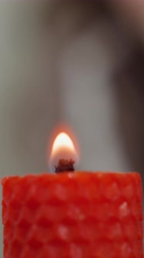 Close Up of Red Candle Flame with Blurred Figure in Background