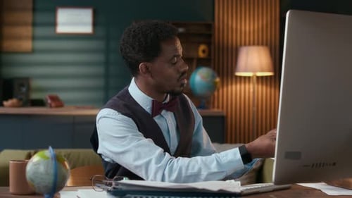 Man at Desk Reviews Papers and Computer