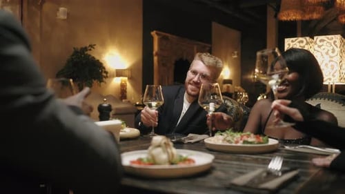 Différentes personnes dînent au restaurant, grillent et font clignoter des verres, du champagne, une fête entre amis