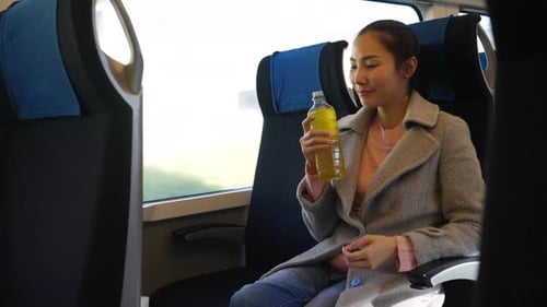 Woman Relaxing on Train Journey with a Drink