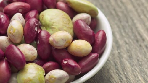 Colorful Beans Filling a White Bowl on Wood