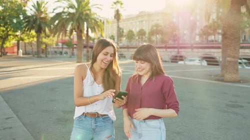 Two Women Friends Laughing at Phone in City