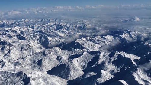 Magnificent panoramic hyperlapse of the Alps mountains viewed from the sky in winter, covered in sno