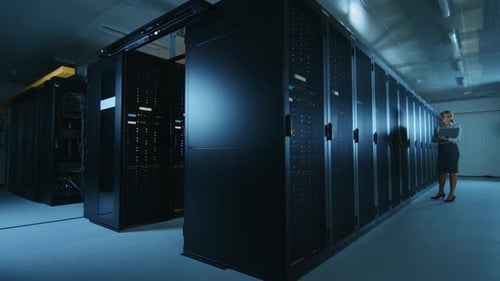 In Data Center Female IT Specialist Walks along the Row of Operational Server Racks, Checking Norma
