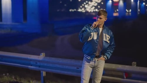 Man Smoking at Night Under a Bridge