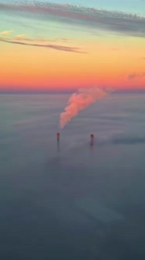 Smokestacks Emerging from Fog at Sunrise