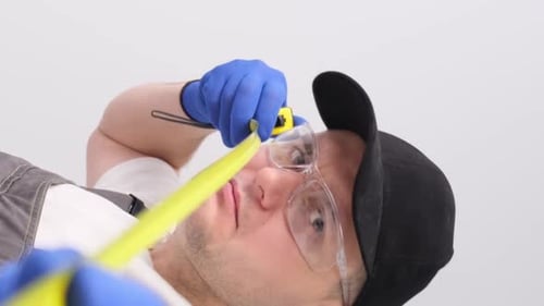 Male Builder on a White Background with a Tape Measure in His Hands Vertical Video