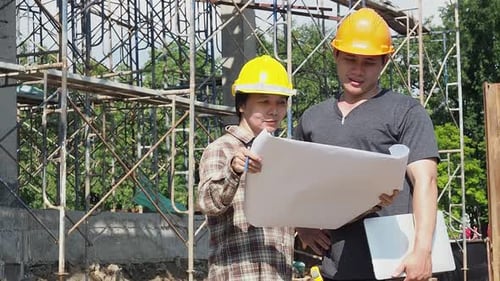Construction manager and engineer discussing and checking plans on construction site.