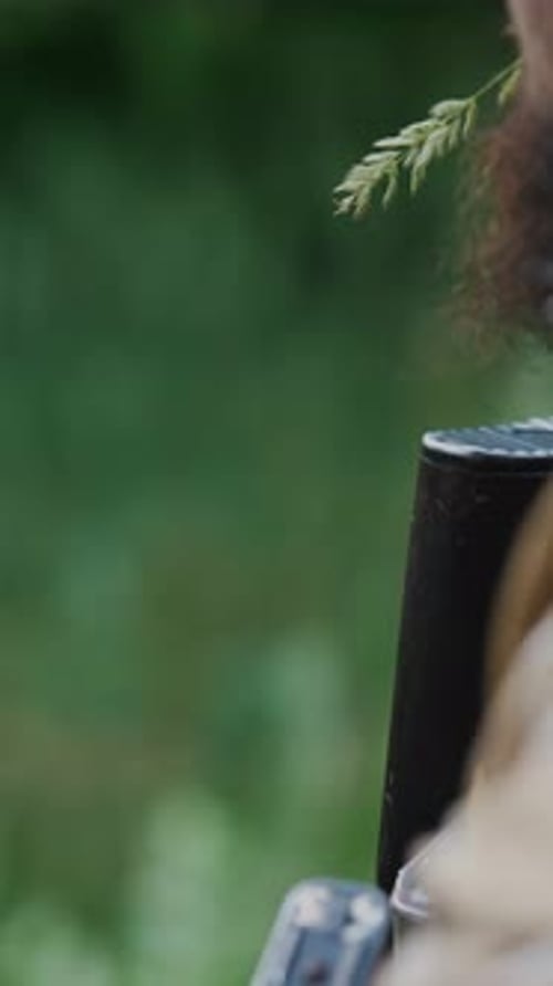 In a Wooded Area a Soldier with a Beard is Armed and Ready