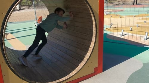 Girl Crawls Through Tunnel in Playground on Sunny Day