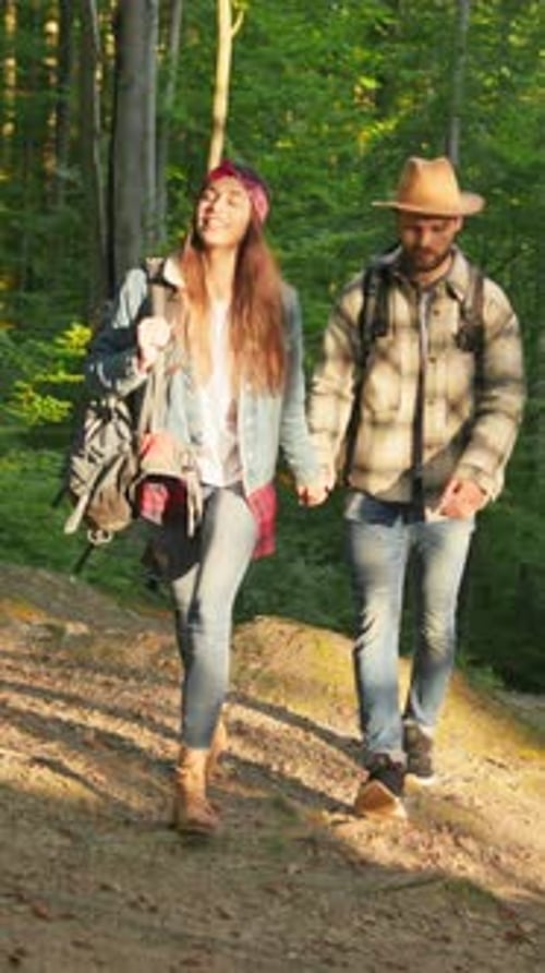 A Couple is Enjoying Hiking Together in a Lush Green Forest During a Bright Sunny Day