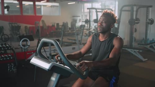 Afroamerikanischer Mann trainiert auf dem Heimtrainer im Fitnessstudio