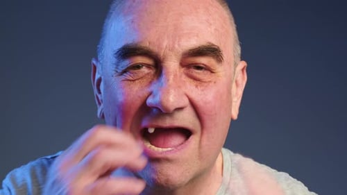 Un homme âgé met de fausses dents dans sa bouche