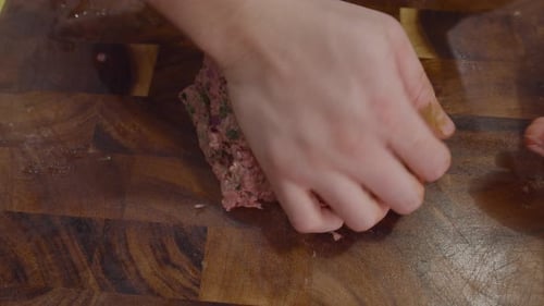 Close up on hands mashing meat on wooden cut board fro making meatballs. Cooking Rigatoni con polpe