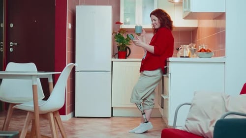 Woman With Prosthetic Leg Uses Mobile Phone in Kitchen