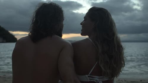 4k video footage of a happy young couple sharing a romantic moment on the beach at sunset