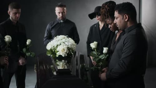 Mourners gathered around casket with flowers