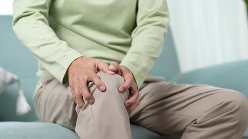 Adult Holding Knee in Pain on Couch