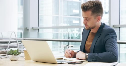 Séquence vidéo 4k d'un beau jeune homme d'affaires travaillant sur son ordinateur portable au bureau