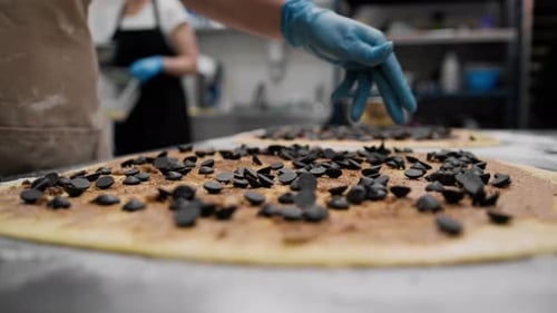 Baker Adding Chocolate Chips to Dough in Kitchen