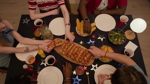 Diverse Friends Sharing Hot Dogs during Independence Day Celebration
