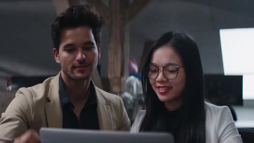 Two Co-Workers Collaborating on a Laptop in Office