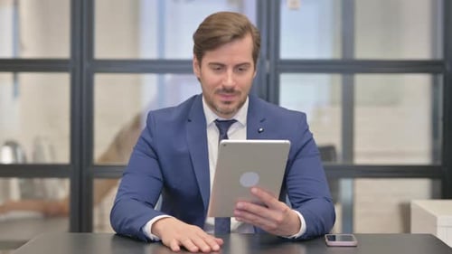 Businessman video conferencing using tablet in modern office