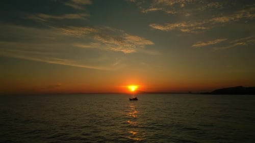 Shooting From a Drone Flying Along the Sea Against the Background of a Sunset and a Fishing Boat