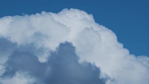 Close-up 4K time lapse video of white big clouds on a blue sunny sky.