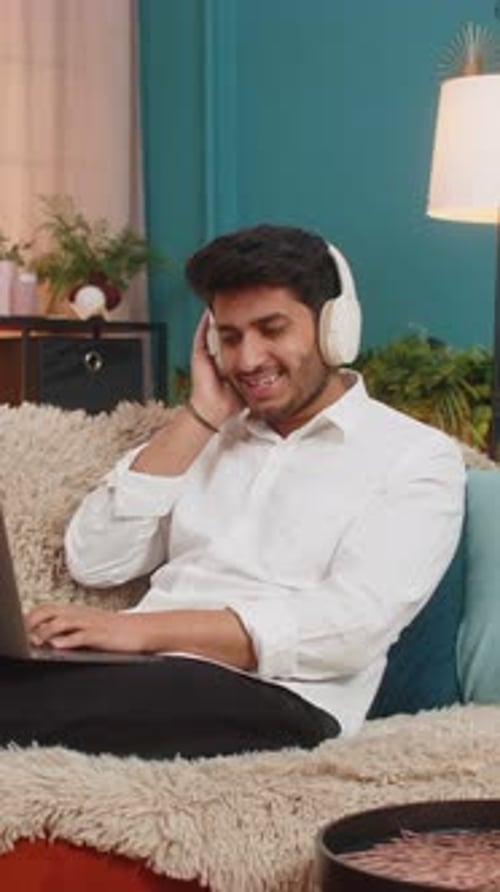 Man Listening to Music While Using Laptop at Home