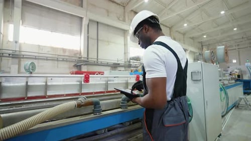 African American Worker in Uniform Checks the Cooling System at the Factory
