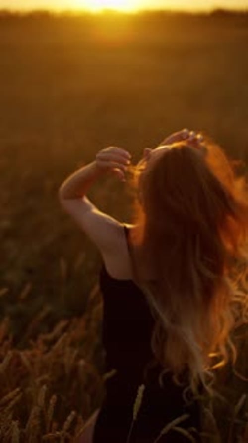 Young Woman Posing in a Wheat Field at Sunset