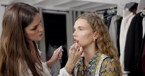 Woman Applying Lipstick to Another Woman Indoors