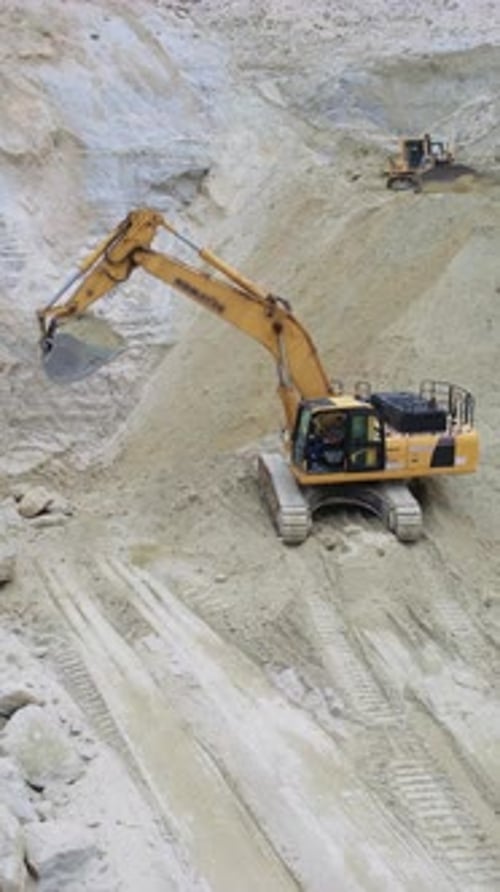 Excavator Scooping Material in a Desert Quarry