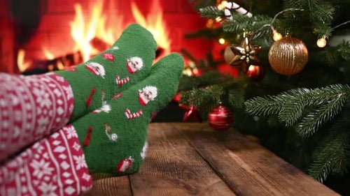 Legs in Christmas Pajamas and Green Socks with Santa Claus and Striped Lollipops Against the