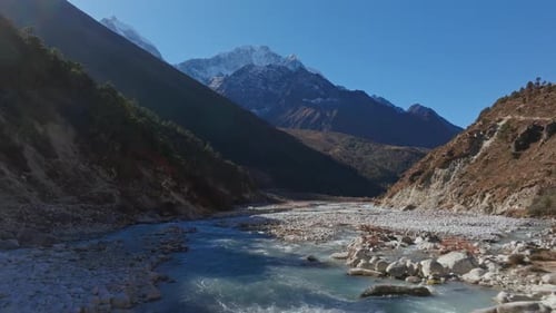 Winding Himalayan River Carving Rocky Terrain Unveiling Snow Dusted Peaks Against Raw Untouched