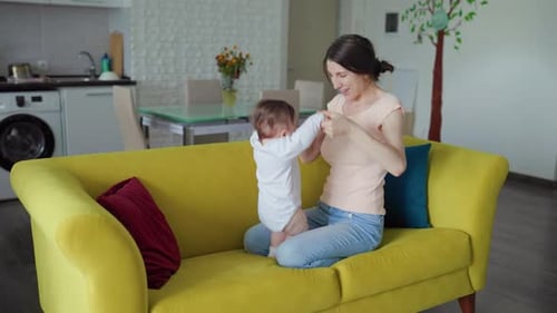 Mother Playing with Baby on a Yellow Couch