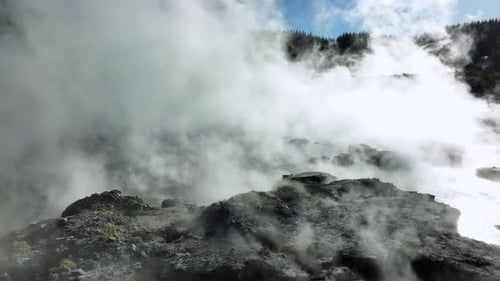 Extrem dampfende Schlammbecken, Drohne, die langsam über die geothermische Landschaft fliegt. Bäume, Dampf, sprudelnder Schlamm