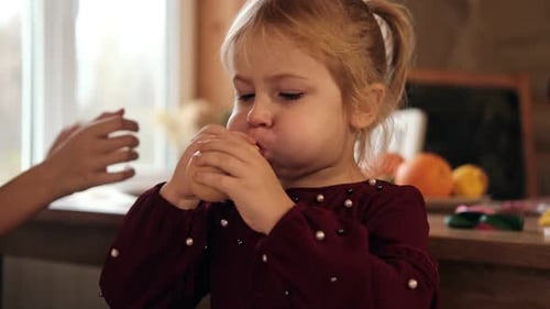 Blonde Child Blowing Up Balloon Indoors
