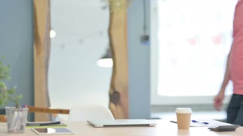 Man Arrives and Opens Laptop at Modern Desk