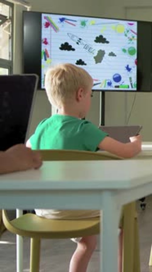 Vertical video: Turning boy in green shirt to screen, raising hand to answer at school with tablet