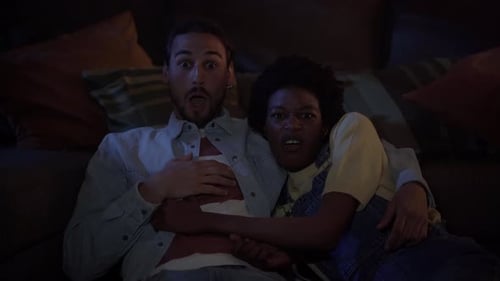 Young Multicultural Couple with Surprised Face Watching Horror Movies or Series at Night Home