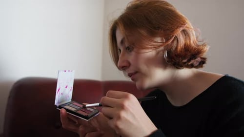 Woman Applies Eye Shadow with Brush at Home