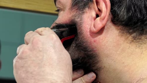 Man Trimming Beard with Electric Shaver, Close Up