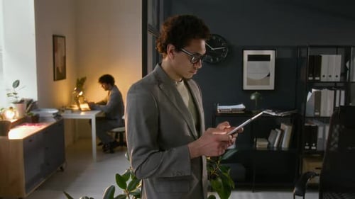 Young Businessman Creating and Editing Documents Using Digital Tablet in Office